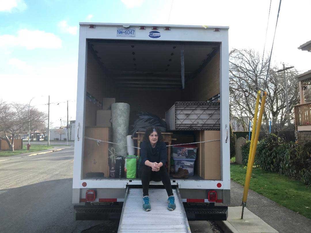 Lynne sitting on the back of a partially full moving truck