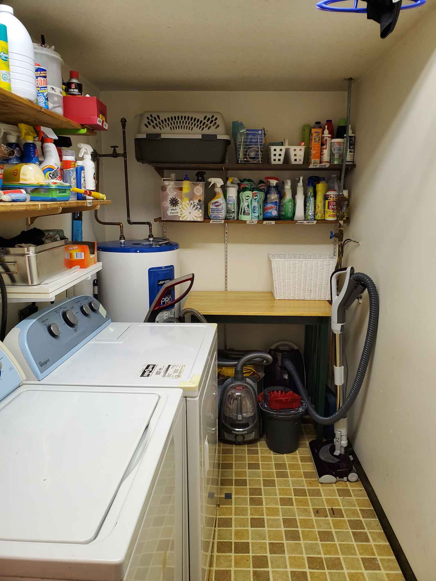 A laundry room with the side table, dryer and floor space cleared except for essential items