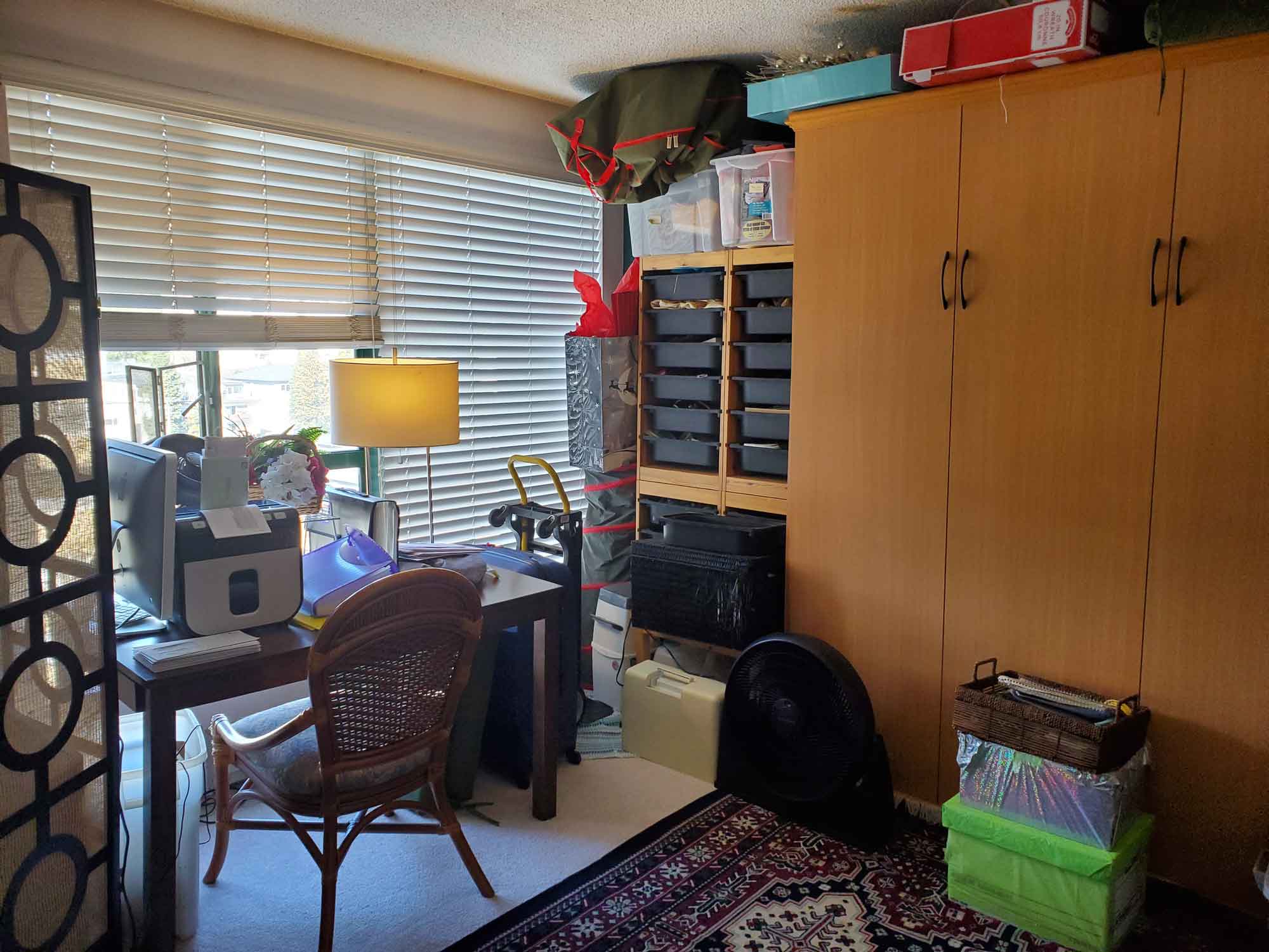 A spare room with boxes piled in various areas of the floor and on a desk