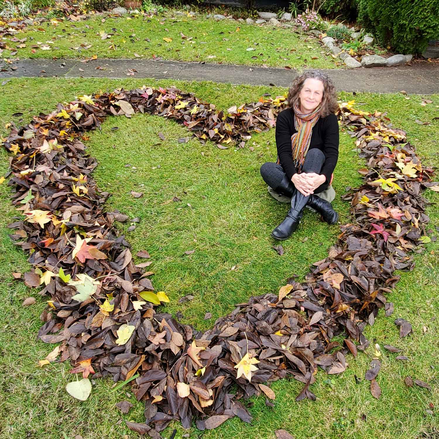Lynne Jamieson smiling at the camera sitting inside a heart made of leaves